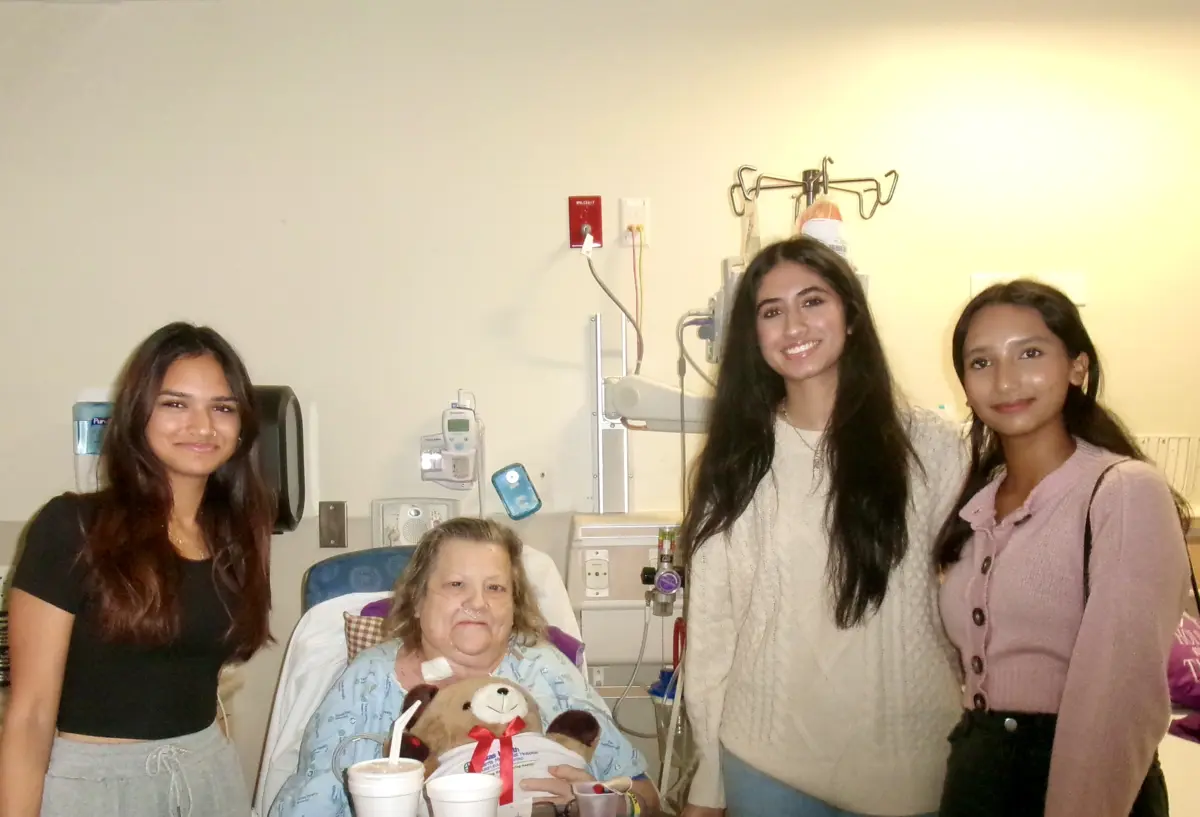 Heart to Heart volunteers visiting a patient on the cardiology floor with a card and a teddy bear.