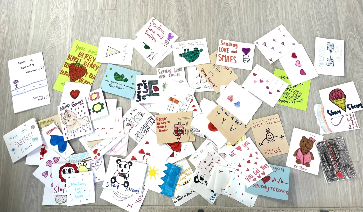 Dozens of handmade get-well cards spread out, reading 'Sending Love and Smiles.'